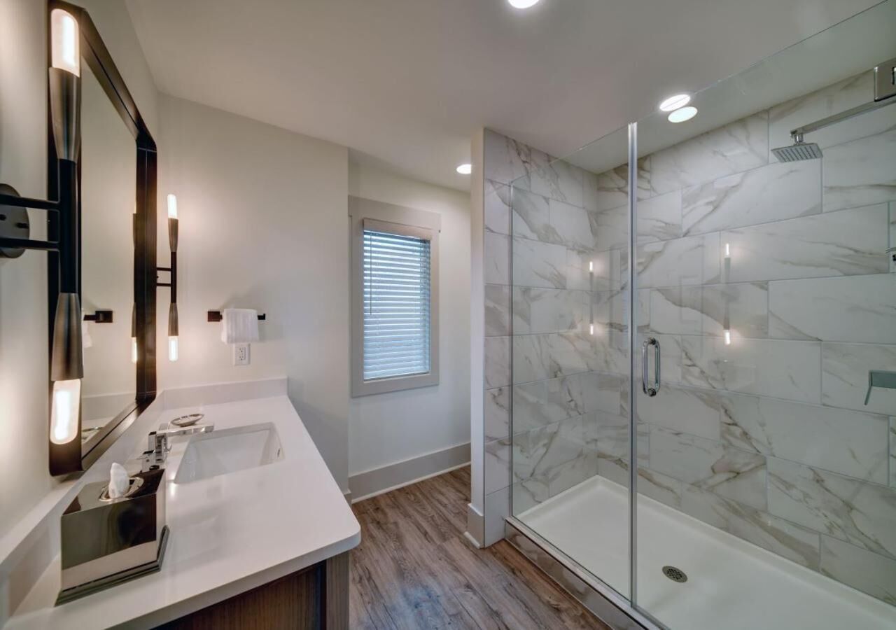 Une salle de bain moderne avec une douche à parois de verre, un grand miroir et un meuble-lavabo.