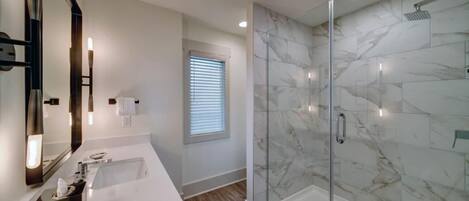 Une salle de bain moderne avec une douche à parois de verre, un grand miroir et un meuble-lavabo.