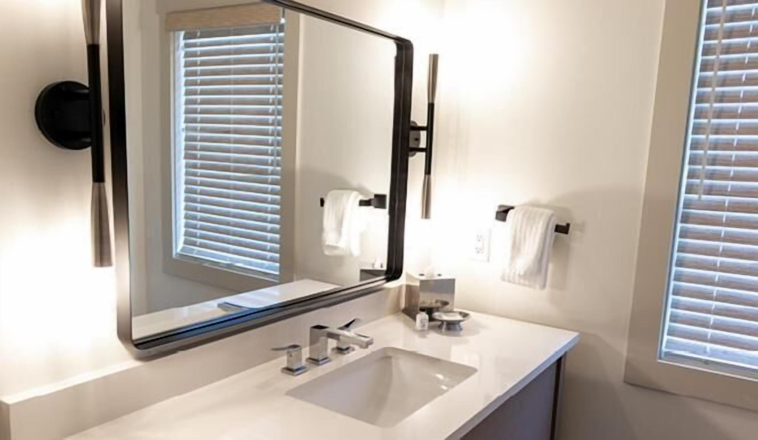 Un bany modern amb un mirall gran, un lavabo i dues barra de tovalloles.