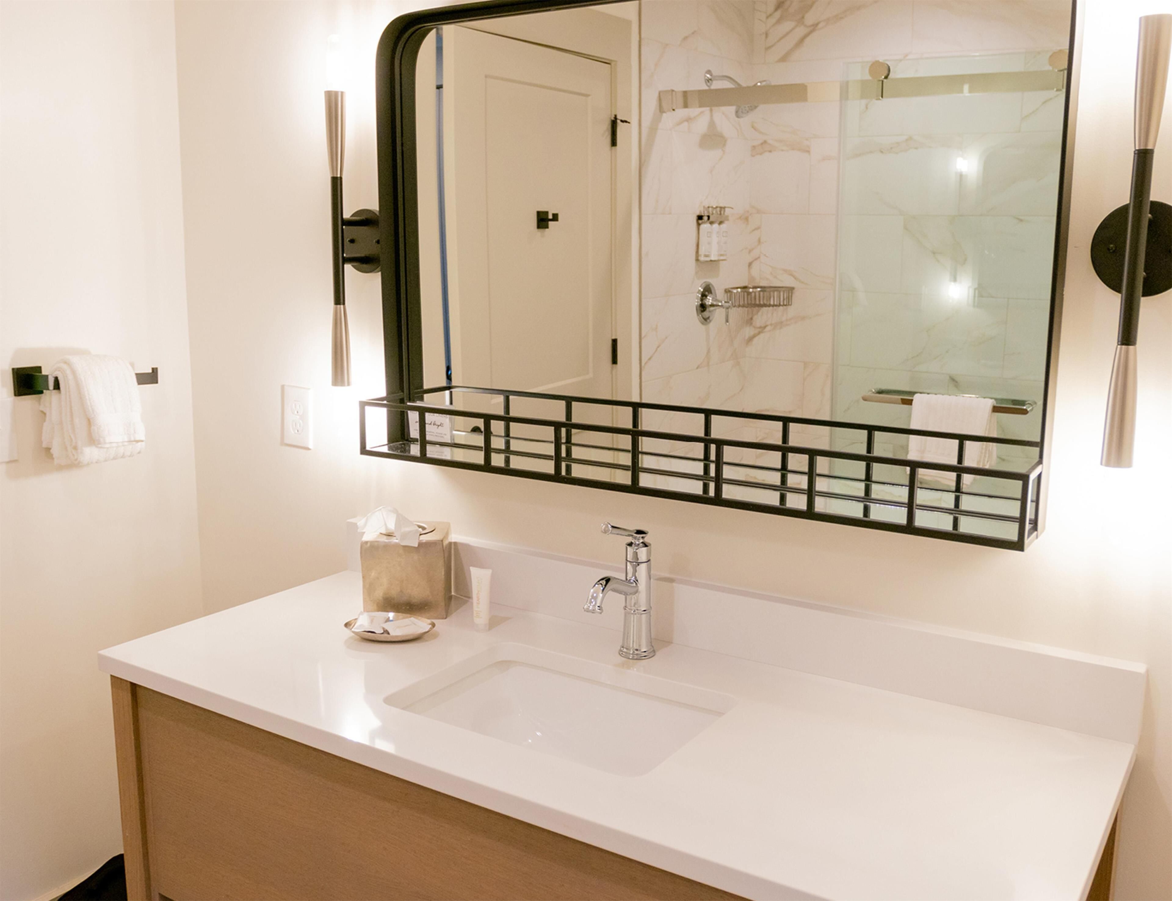 Une salle de bain avec un lavabo blanc, un miroir et un porte-serviettes.