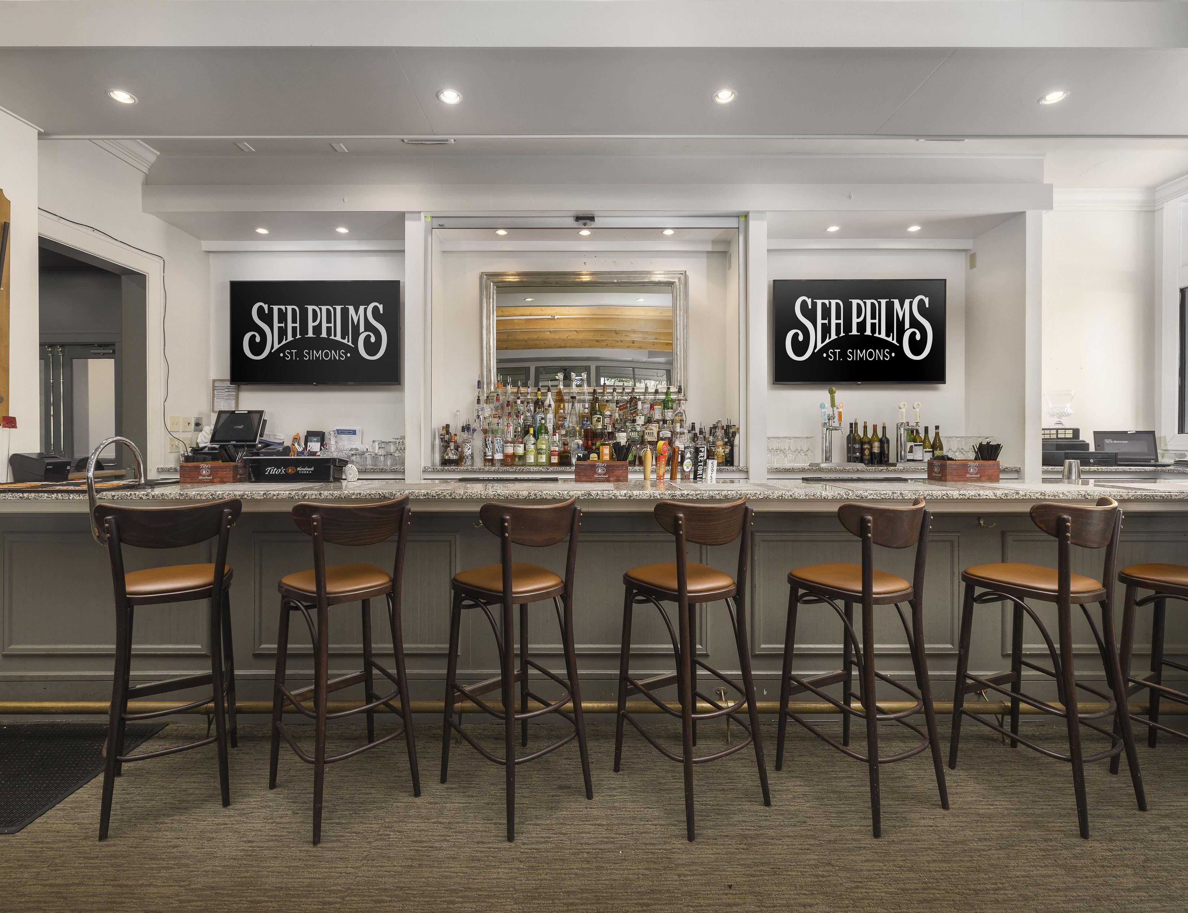 A bar area with a counter, multiple stools, and a well-stocked bar.