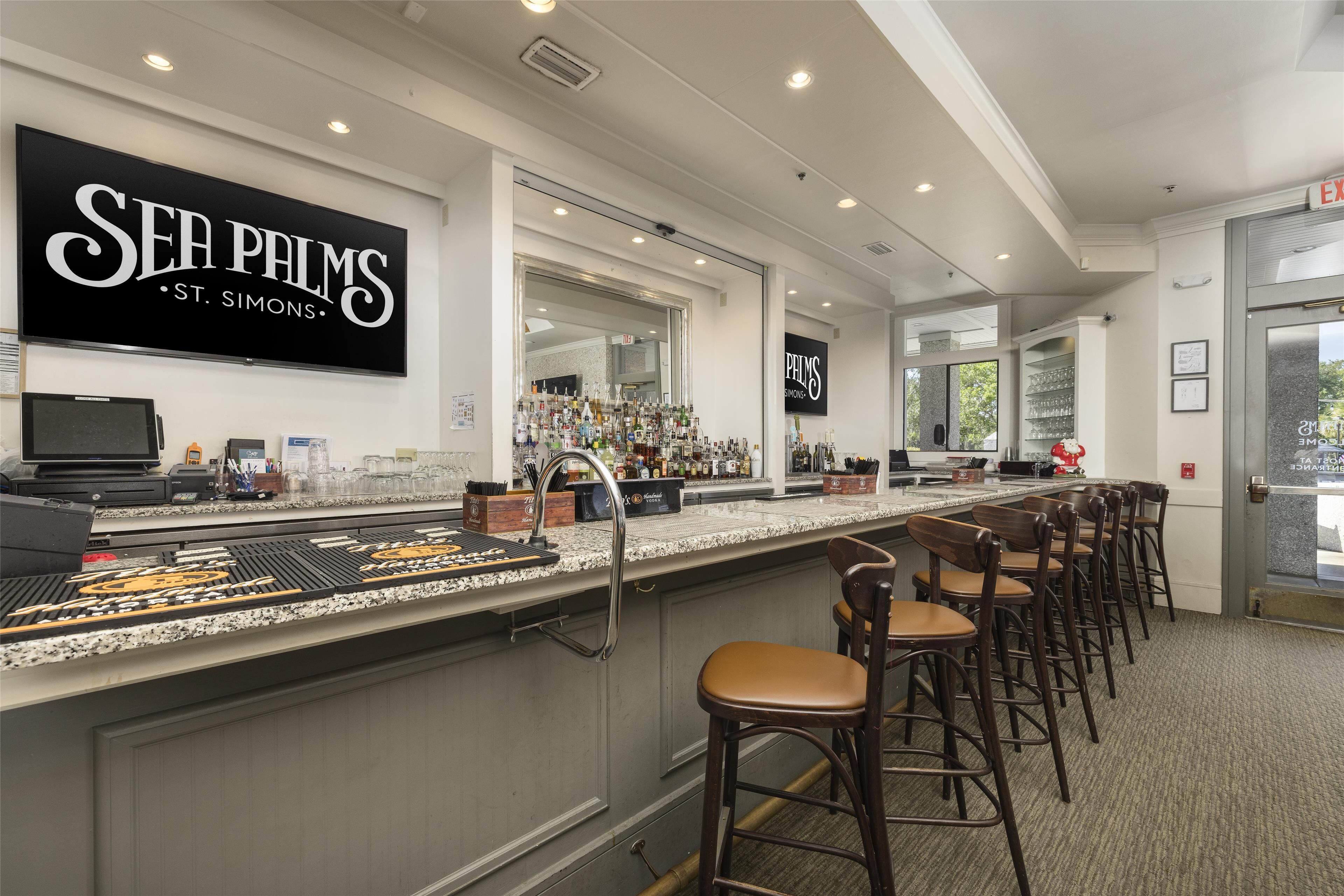 A bar area with a sign reading "SEA PALMS ST. SIMONS" and a counter with various bottles and glasses.