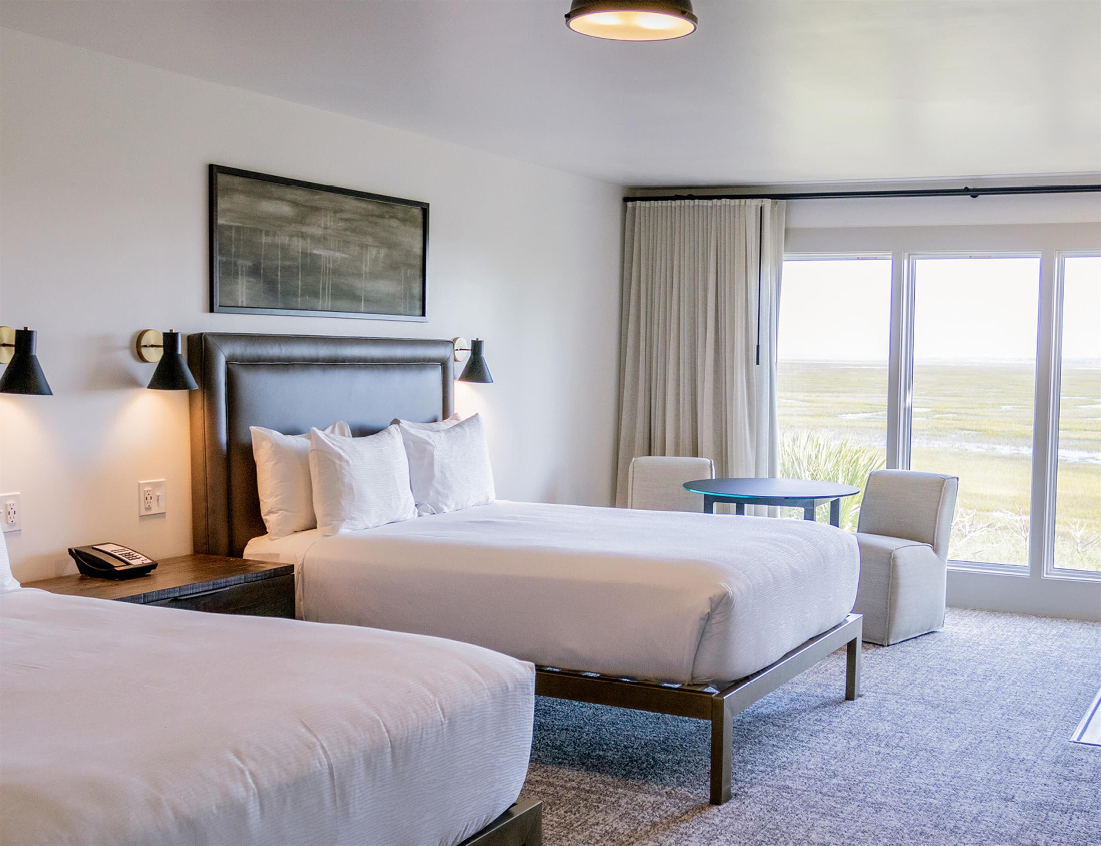 Una habitación de hotel con dos camas, un escritorio, una silla y vistas al exterior.