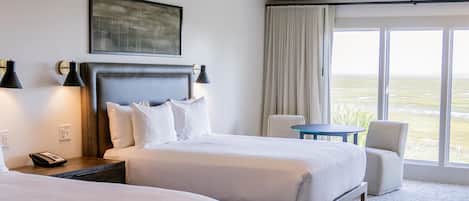 Una habitación de hotel con dos camas, un escritorio, una silla y vistas al exterior.