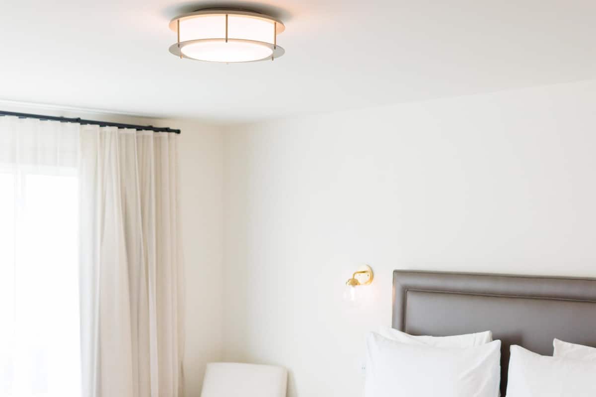 Habitación de hotel con una cama grande, una mesita de noche, una silla y una lámpara fijada en la pared.