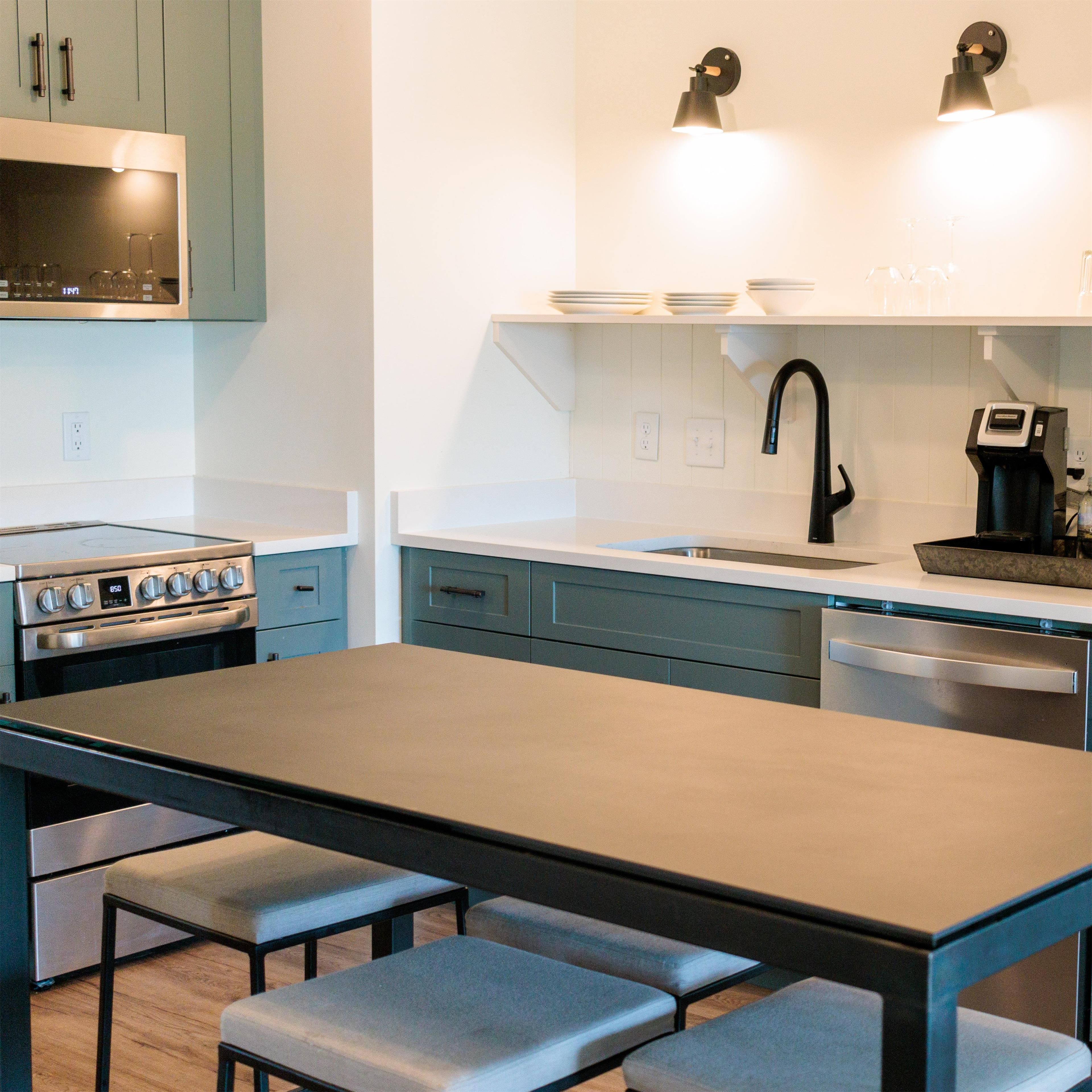 A modern kitchen with a stainless steel stove, a black faucet, and a coffee machine.