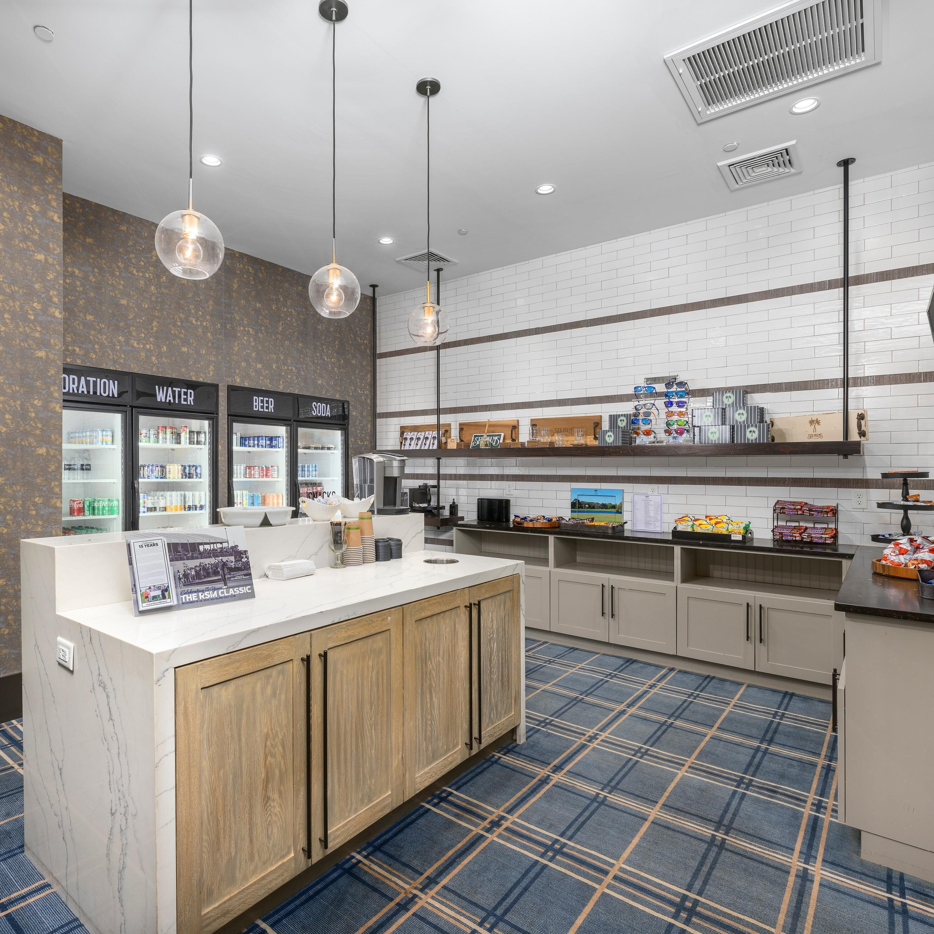 A clean, modern kitchenette with a marble countertop, a coffee station, and a beverage fridge.