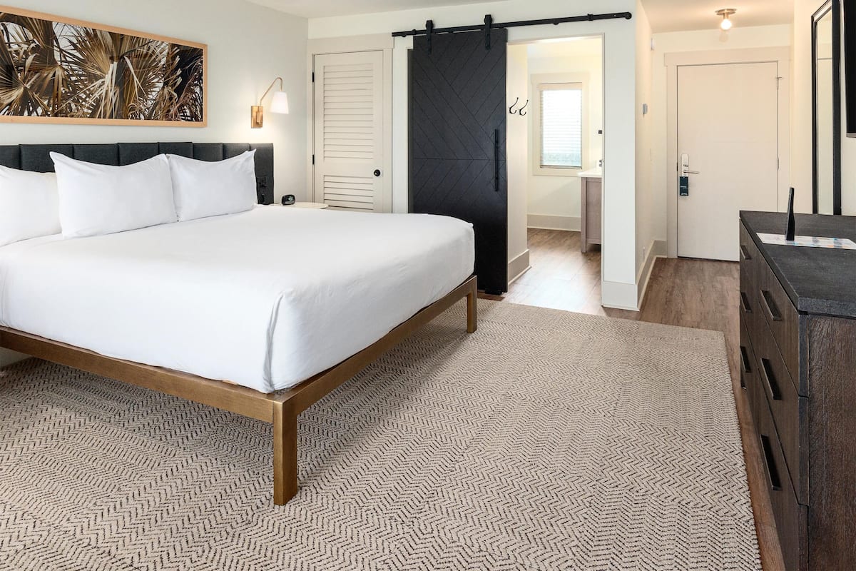 Una habitación de hotel moderna con una cama grande, un escritorio y una puerta corredera que da a un baño.