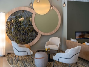 Un espace de détente moderne doté d’un élément décoratif mural circulaire, de sièges, d’une table basse et d’un téléviseur.