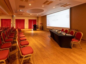 A conference room with rows of red chairs, a long table with water bottles, and a projector screen displaying 'MERCURE HOTELS'. - Mercure Auxerre Autoroute du Soleil (Appoigny)
