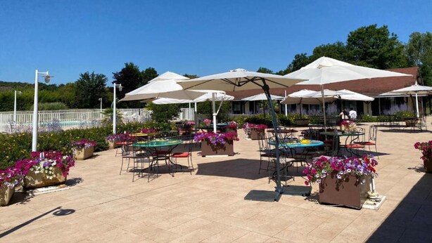 Un patio al aire libre con varias mesas y sillas, rodeado de sombrillas blancas.