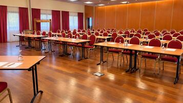 A conference room with rows of tables and chairs, equipped with water bottles and glasses.