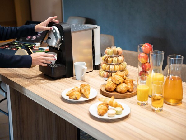 A breakfast buffet with a coffee machine, pastries, and juice.