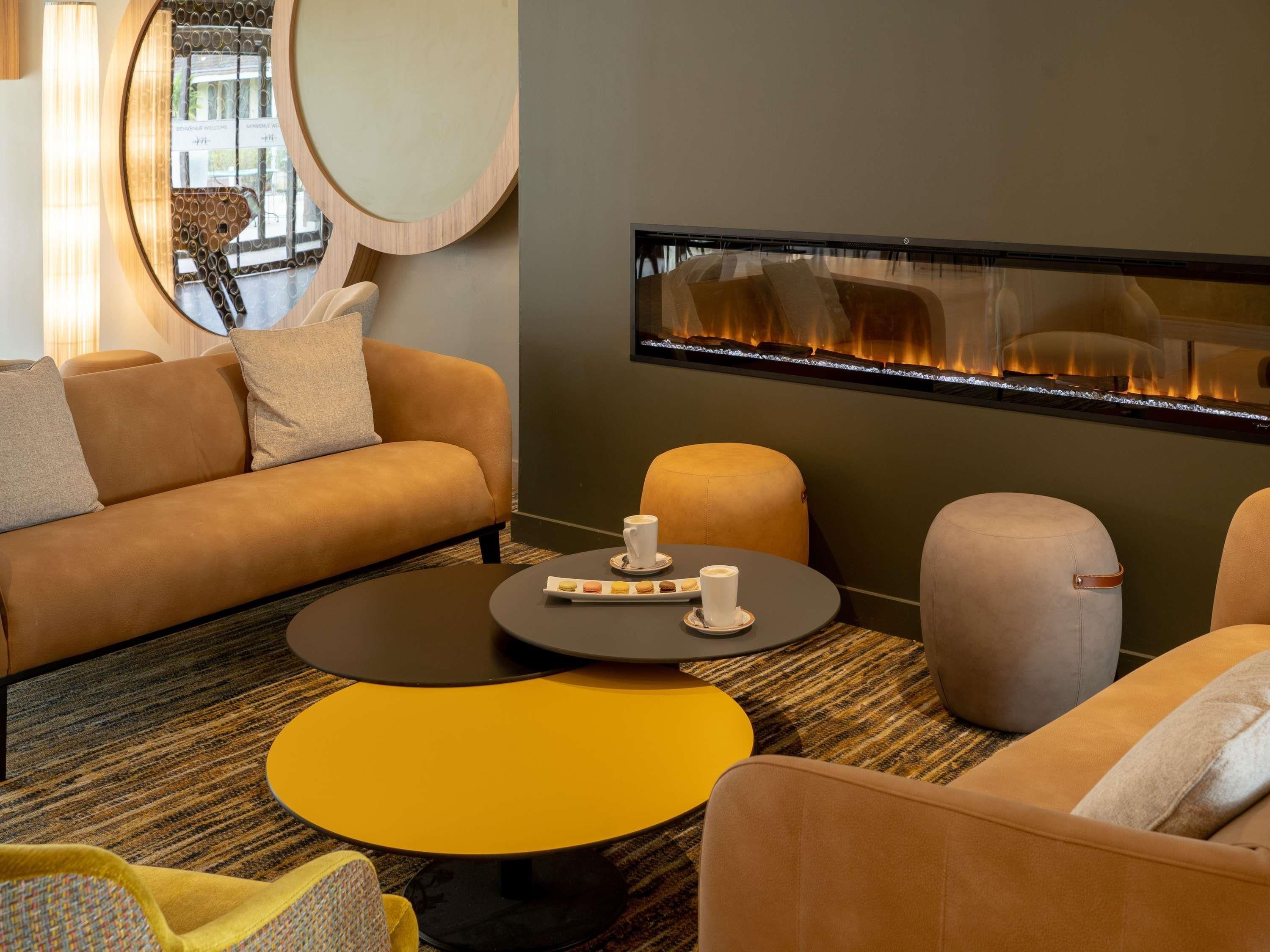 Una sala moderna con sofá, reposapiés, mesa de centro y chimenea.