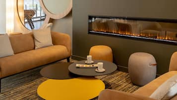 Una sala moderna con sofá, reposapiés, mesa de centro y chimenea.