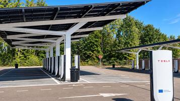 Une borne de recharge Tesla dotée de plusieurs points de recharge, d’un espace de stationnement couvert et d’un ciel dégagé.