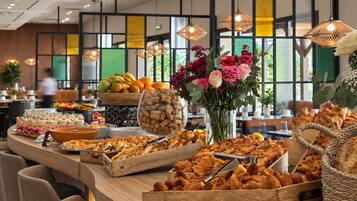 A buffet with various food items and a vase of flowers.