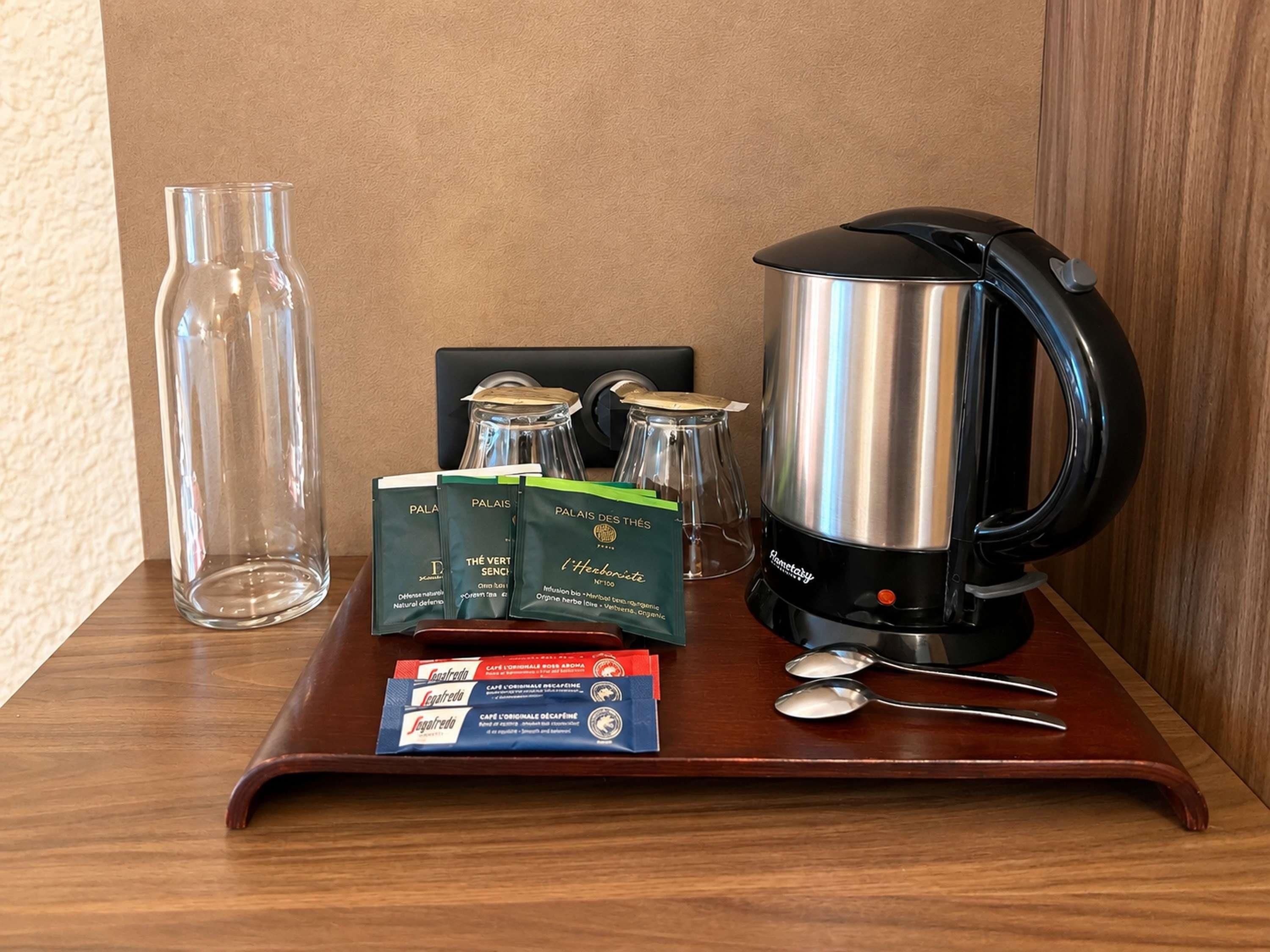 A wooden tray with a coffee maker, a glass bottle, and some packaged items.