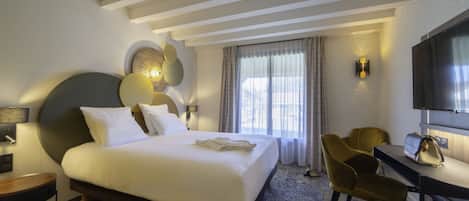 A hotel room with a large bed, a desk with a chair, a television, and a window with curtains.
