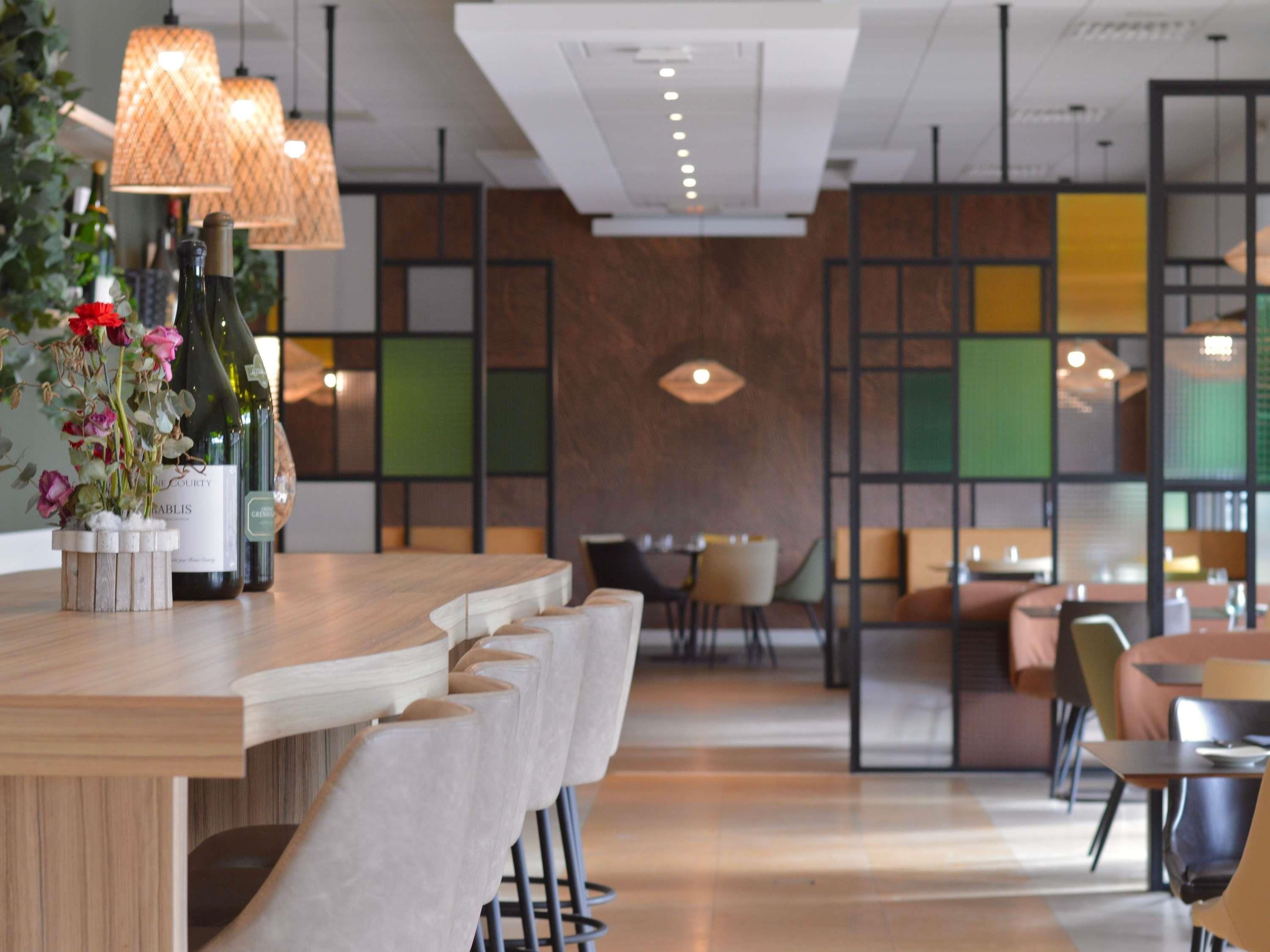 A modern restaurant interior with a bar area, seating, and decorative elements.