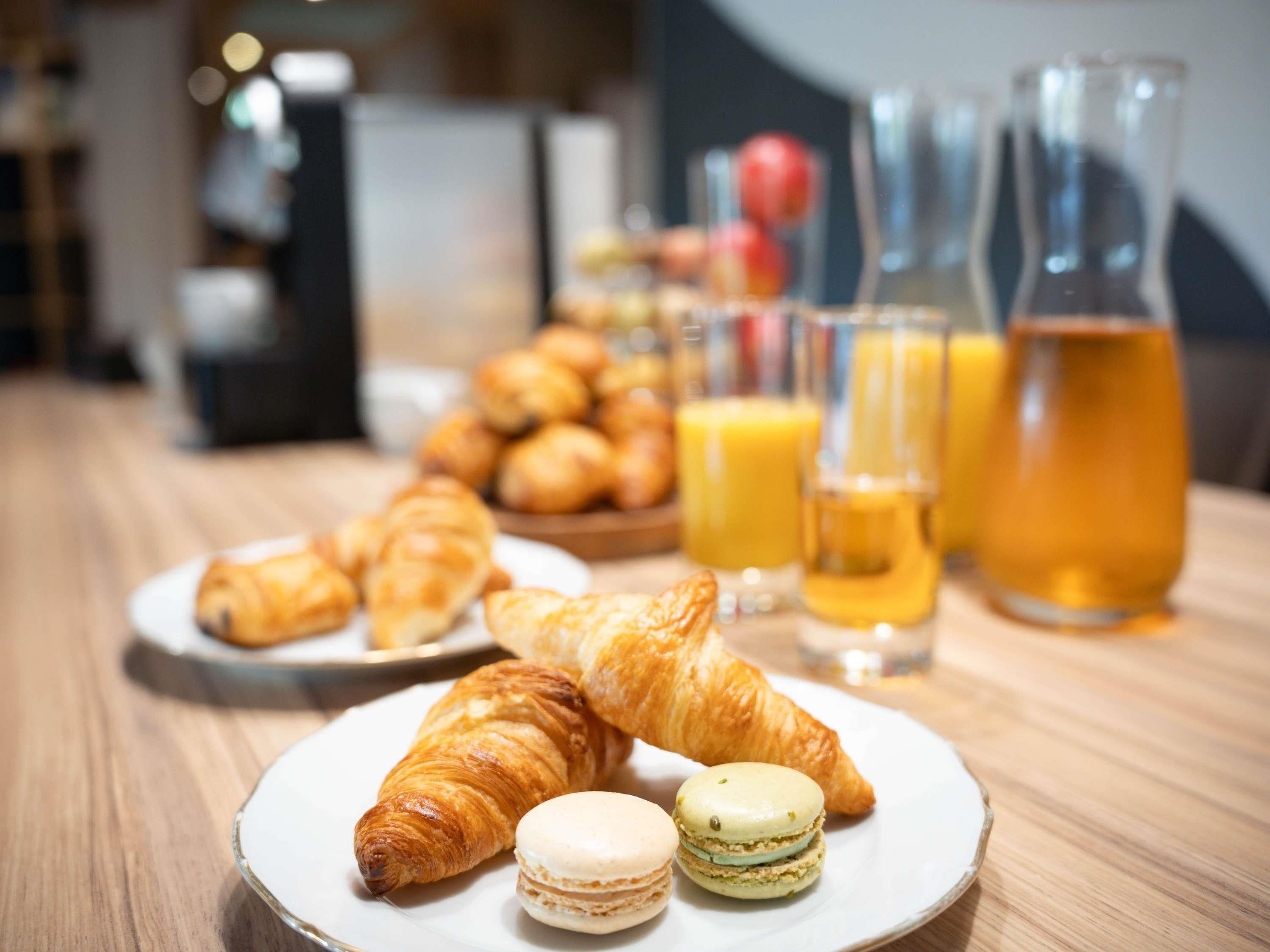 Ein Frühstückstisch mit Croissants, Macarons und Orangensaft.