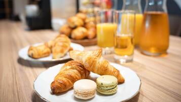 Ein Frühstückstisch mit Croissants, Macarons und Orangensaft.