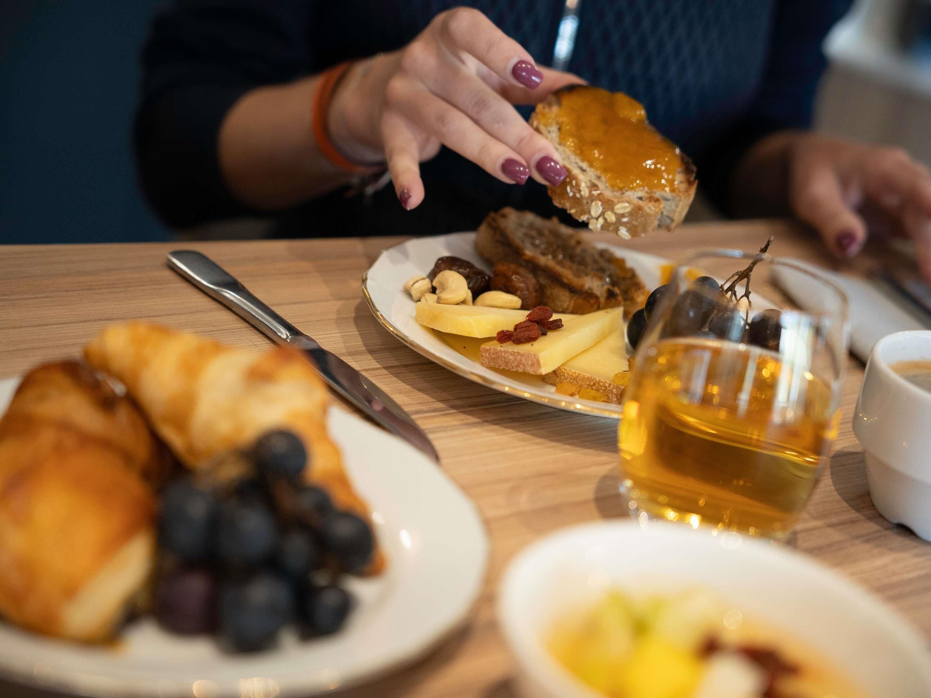 A dining table with a plate of food, a glass of amber liquid, and a knife.
