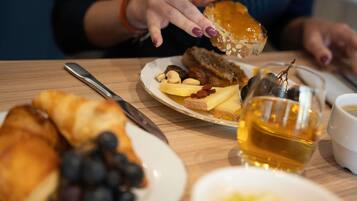 A dining table with a plate of food, a glass of amber liquid, and a knife.