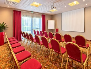 A conference room with rows of red chairs, a whiteboard, and a projector screen. - Mercure Auxerre Autoroute du Soleil (Appoigny)