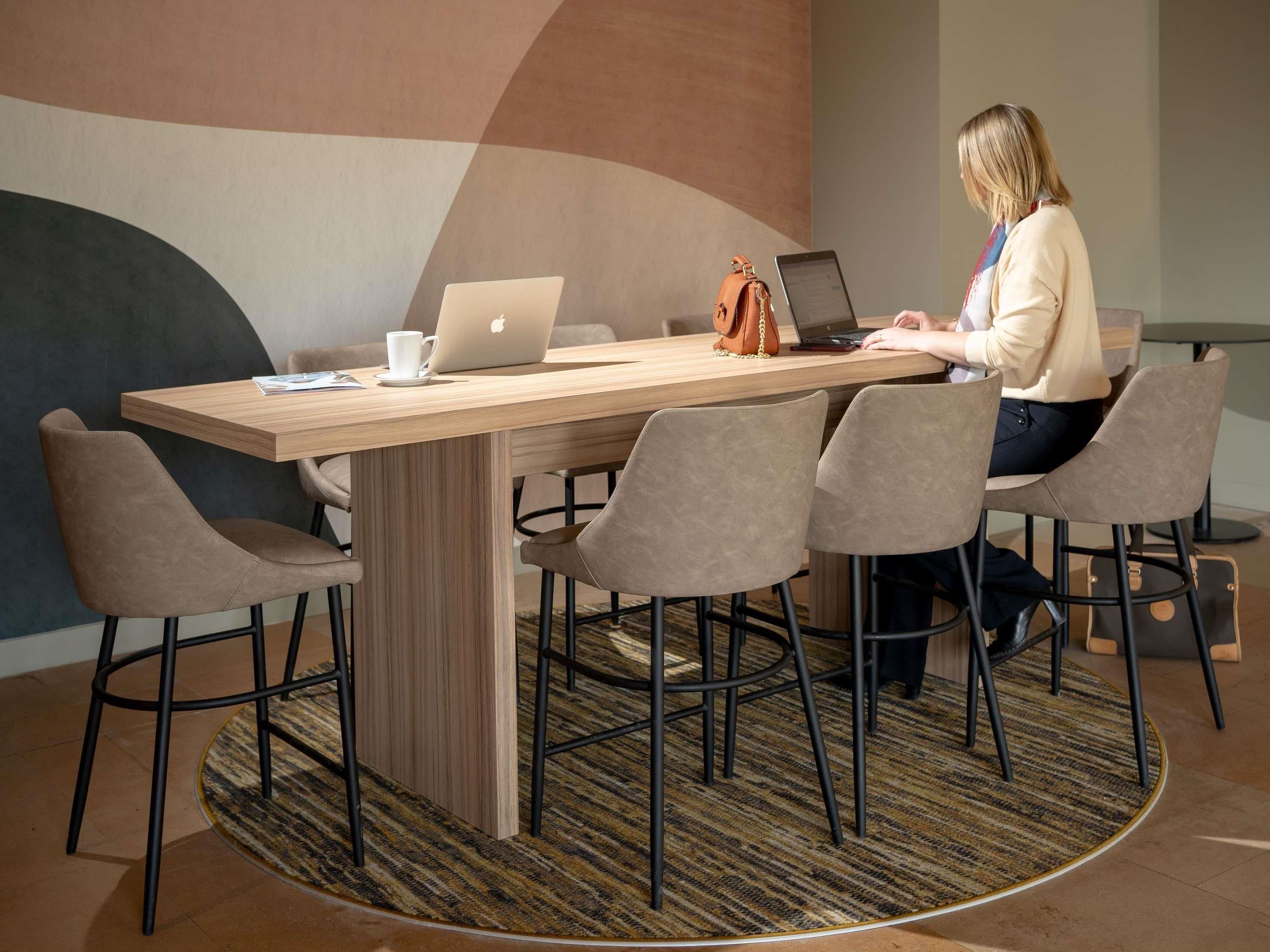 Una sala de conferencias con una mesa de madera, cuatro sillas y dos portátiles.
