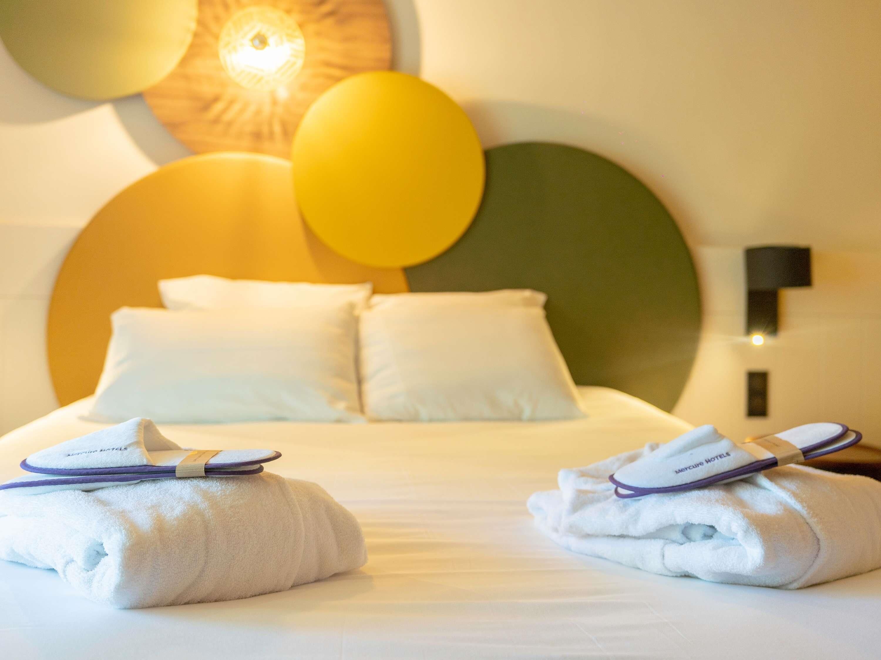 Ein Hotelzimmer mit Bett, Kissen und Handtüchern.