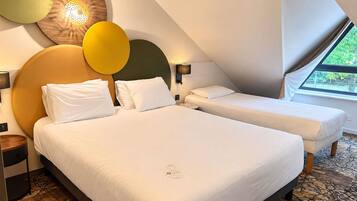 A hotel room with two beds, a large window, and a unique ceiling design.