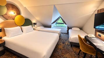 A modern hotel room with a large bed, two smaller beds, a desk with a chair, and a television.