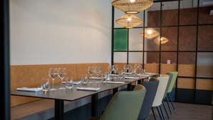 Un comedor con una mesa larga dispuesta para una comida, sillas y lámparas colgantes.