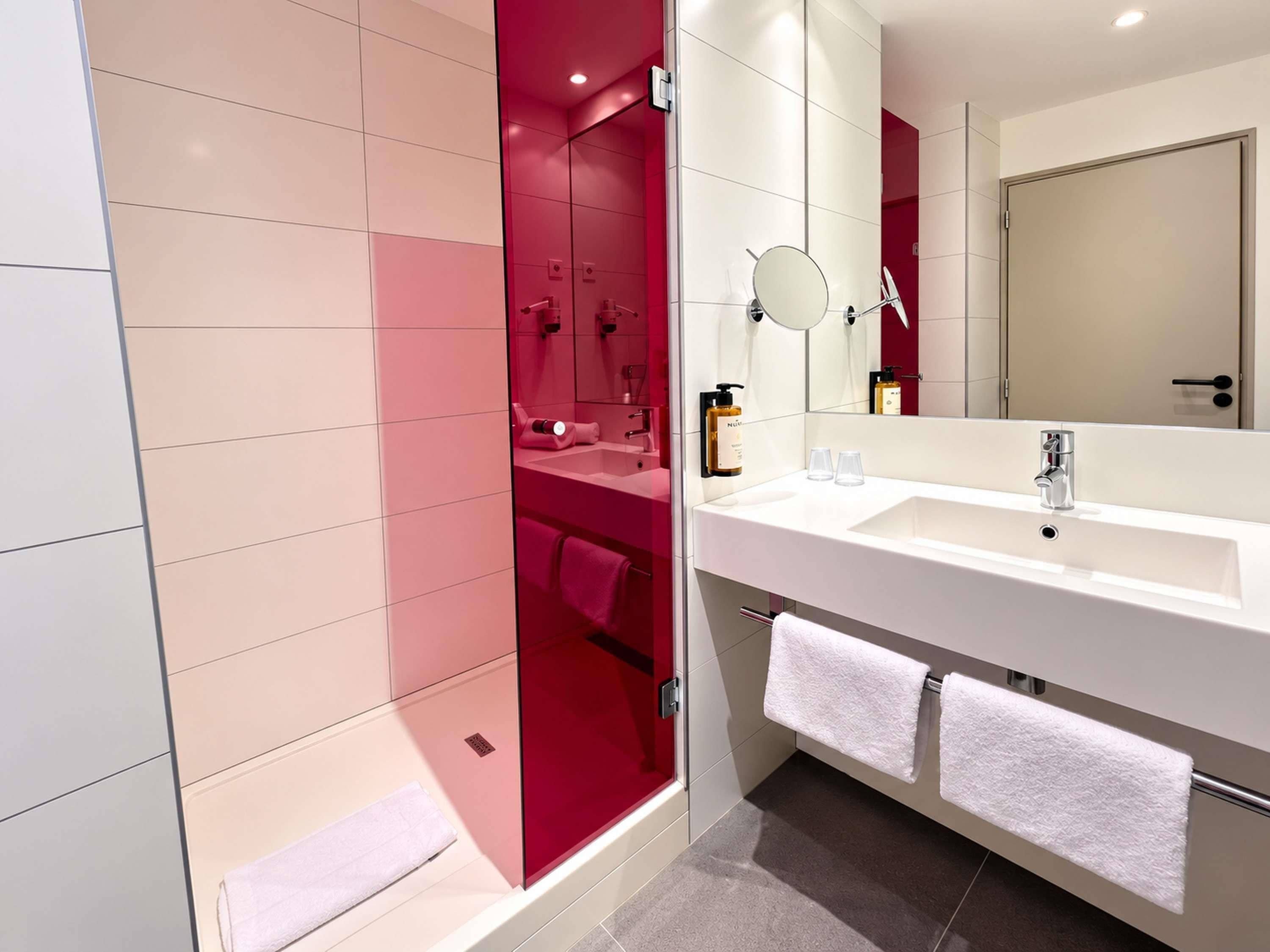A modern bathroom with a glass shower enclosure, a white sink, and a large mirror.