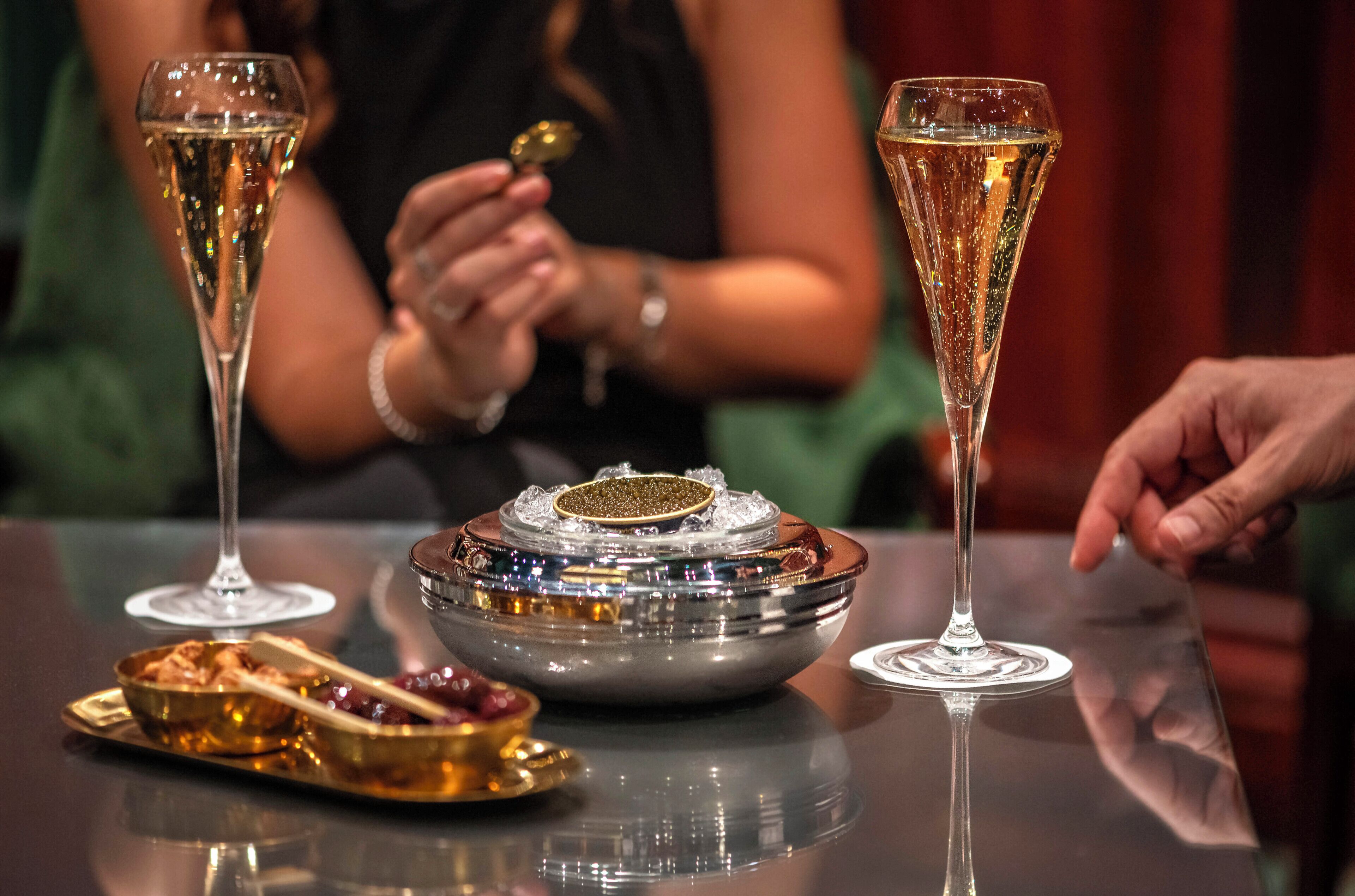 Uma mesa com duas taças de champanhe, uma tigela decorativa e um prato com comida.