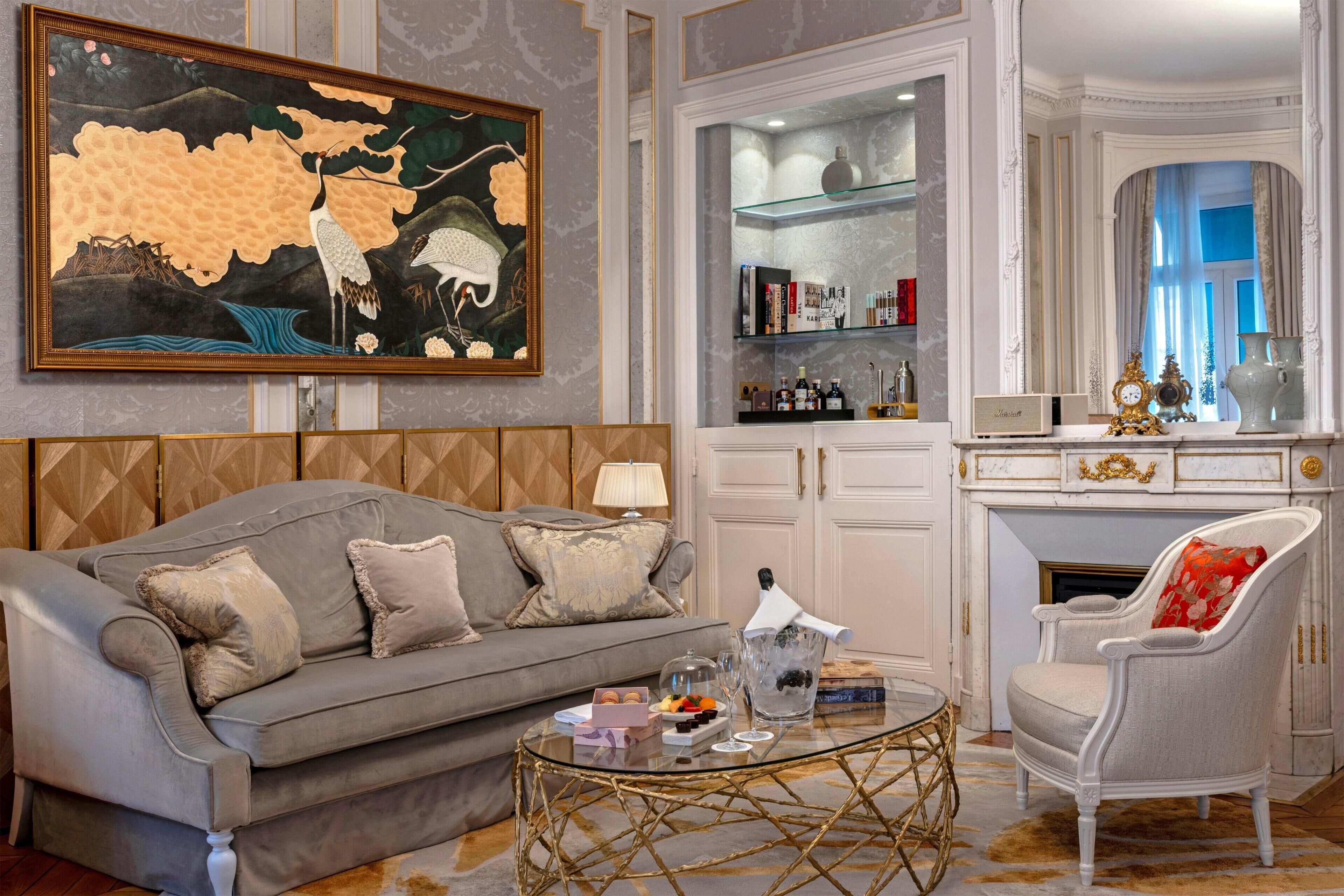 A living room with a sofa, a coffee table, a chair, a painting, and a fireplace.