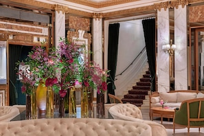 A luxurious interior with a grand staircase, elegant furniture, and decorative vases with flowers.