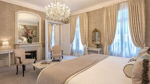 Ein geräumiges Schlafzimmer mit einem großen Bett, einer Sitzecke mit Sessel und Tisch, einem Kamin und einer Kristallleuchter.
