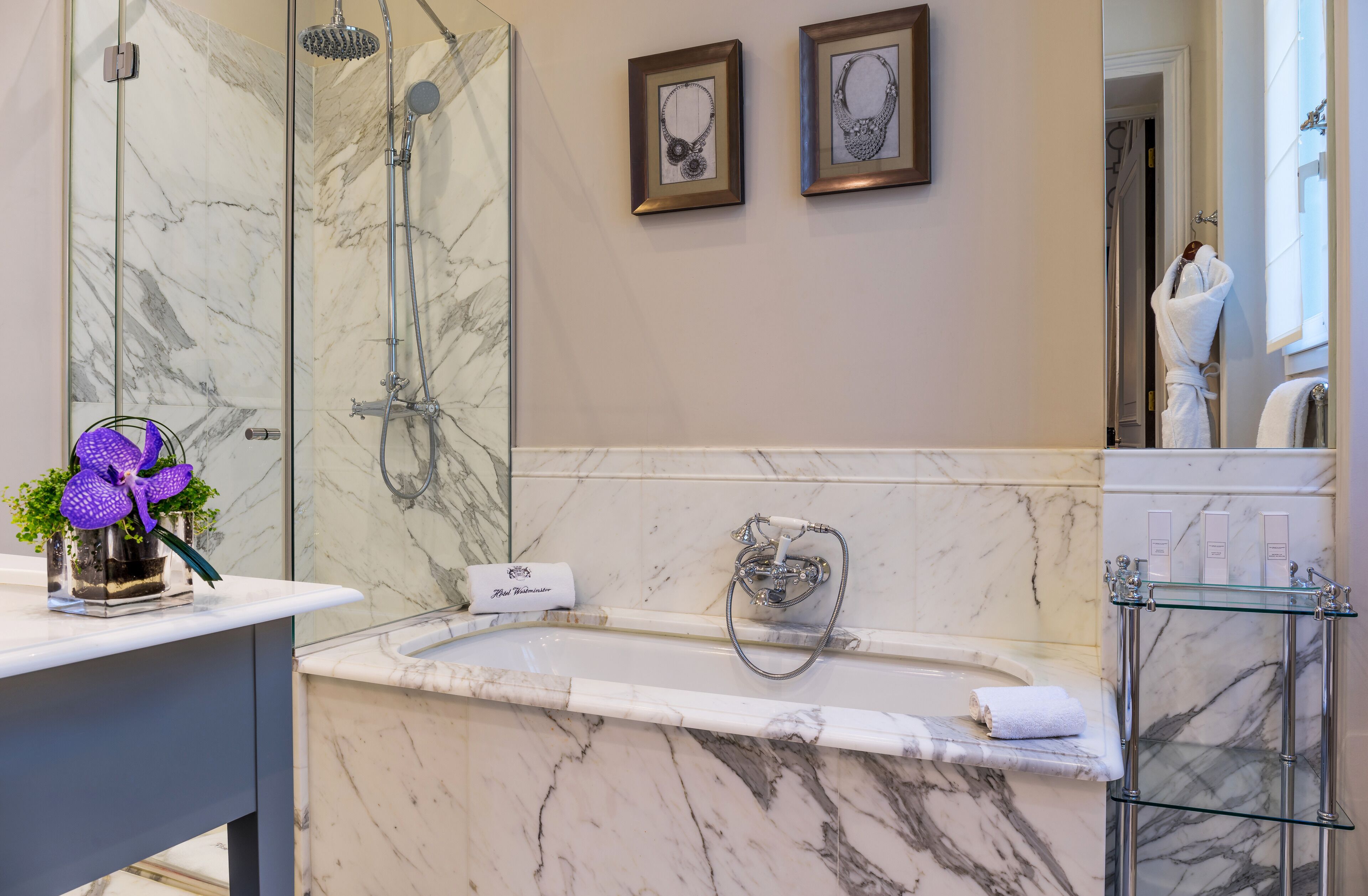 Un bagno con un lavabo in marmo, una doccia e uno scaffale in vetro.