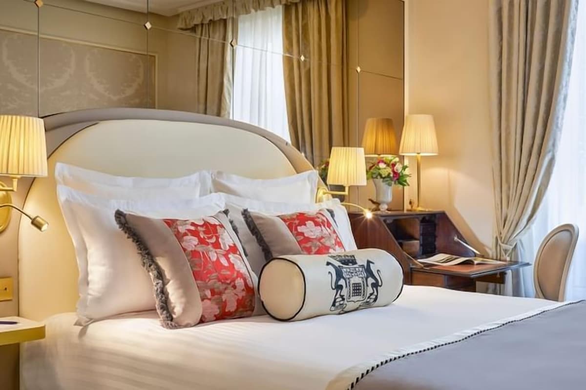 Una habitación de hotel con una cama grande, lámparas de noche, un escritorio y una silla.