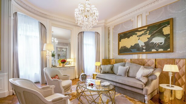 Ein luxuriöses Wohnzimmer mit einer Couch, Sesseln, einem Glastisch und einer Chandelier.