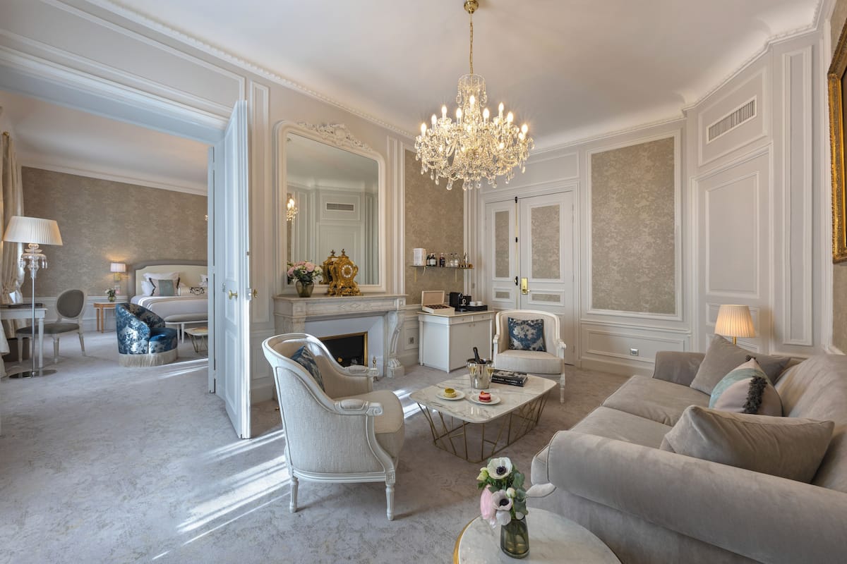 A spacious living room with a chandelier, a fireplace, and a large mirror.