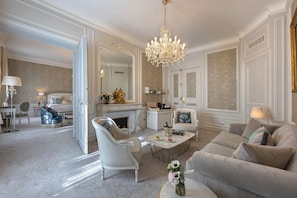 A spacious living room with a chandelier, a fireplace, and a large mirror.