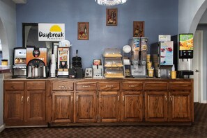 Enjoy a convenient breakfast at this hotel's breakfast bar, featuring a selection of food and beverage options, including a coffee machine, toaster, waffle maker, and refrigerated display cases.
