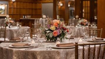 Un espace repas avec des tables rondes dressées pour le repas, agrémenté de compositions florales et de bougies.