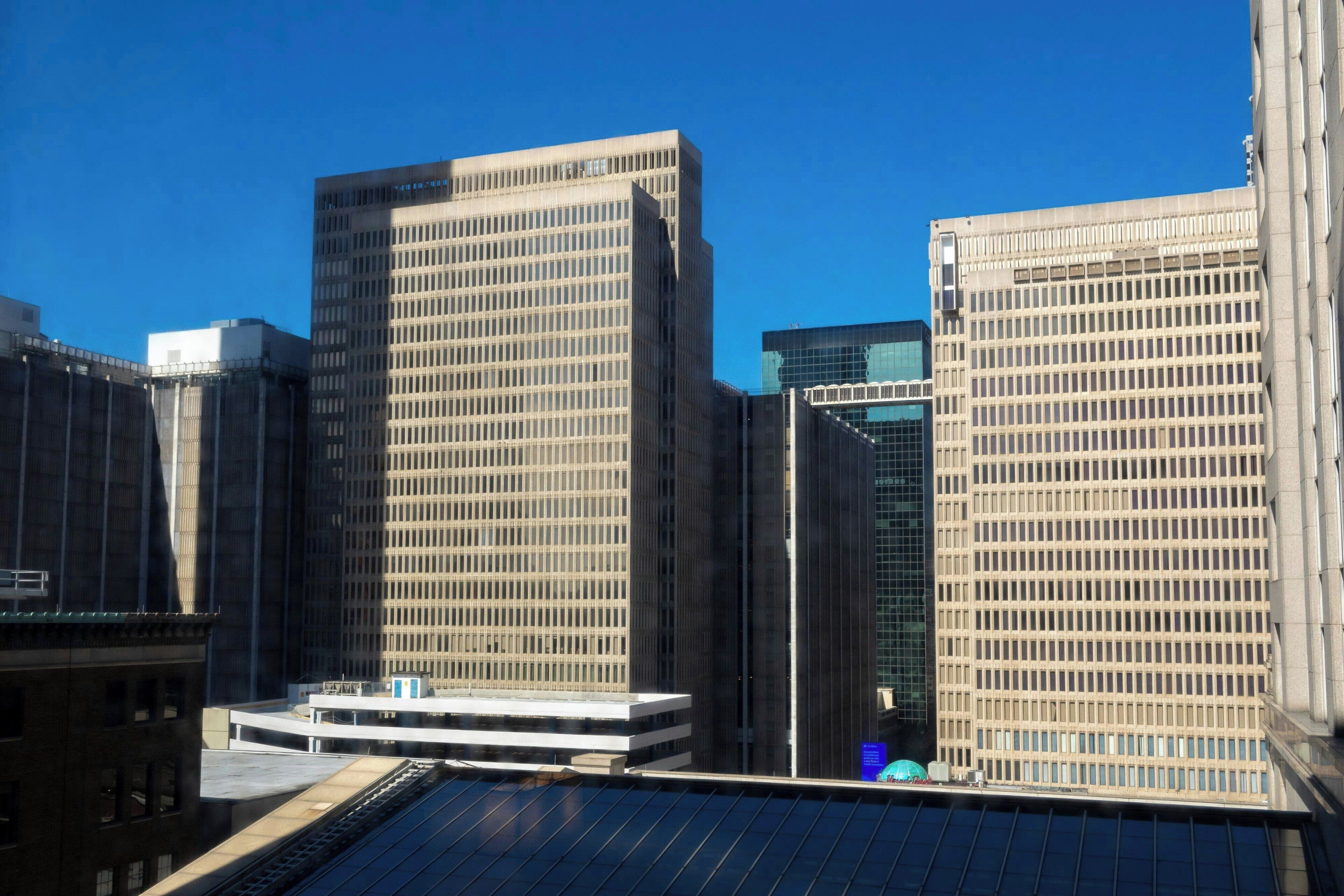 Un paisatge urbà amb edificis alts, incloent una estructura rectangular destacada amb un disseny de reixeta i un edifici modern de vidre.