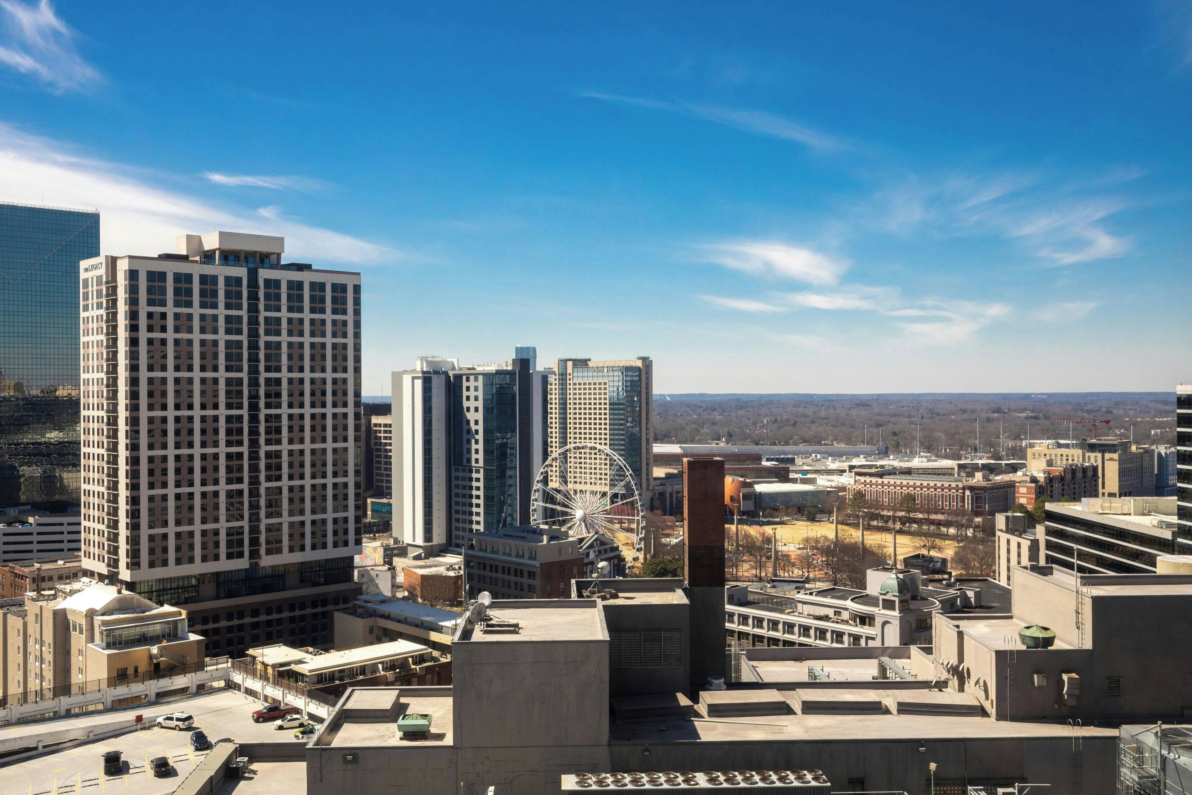A cityscape with modern high-rise buildings, a Ferris wheel, and a clear blue sky.