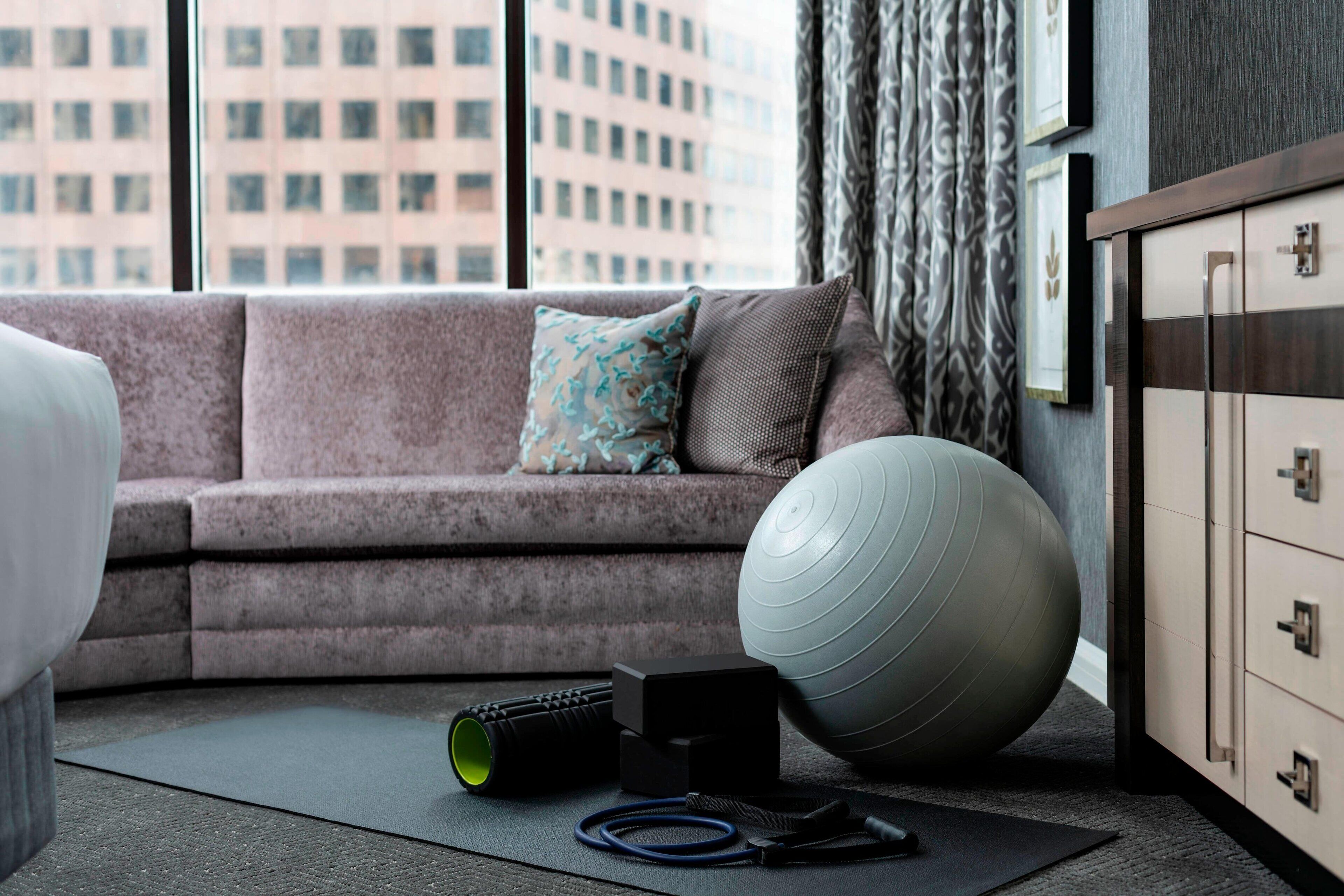 A modern living room with a gray sofa, exercise ball, and fitness equipment.