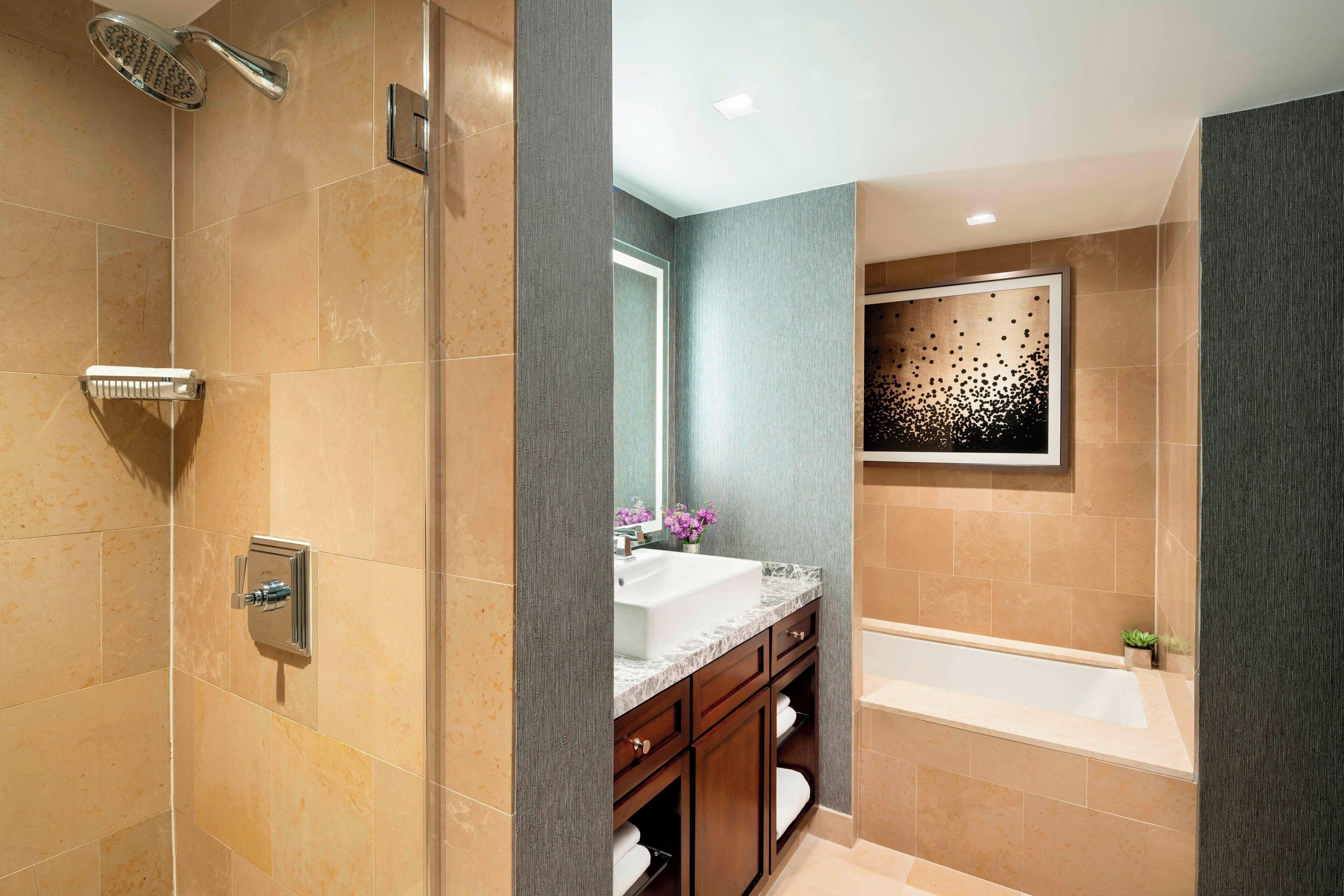 Un baño moderno con ducha, bañera, tocador con lavamanos y espejo.